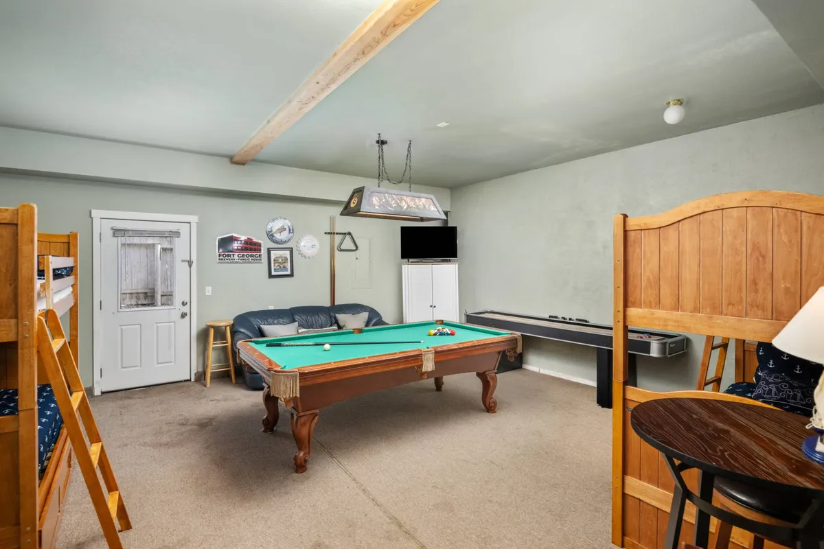 A lively game room featuring a pool table, bunk beds, a seating area, dart board, and a television. The playful layout provides ample space for entertainment and group fun, ideal for families or groups traveling together.