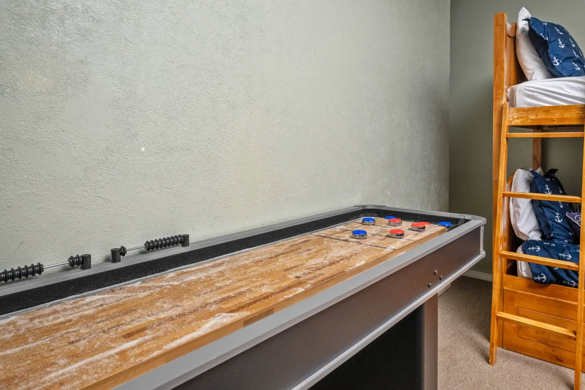 A bright, playful space with a modern shuffleboard table and a set of sturdy bunk beds built in. The room radiates a fun atmosphere, ideal for both games and sleepovers, with ample space for kids or teens to create their own hideout.